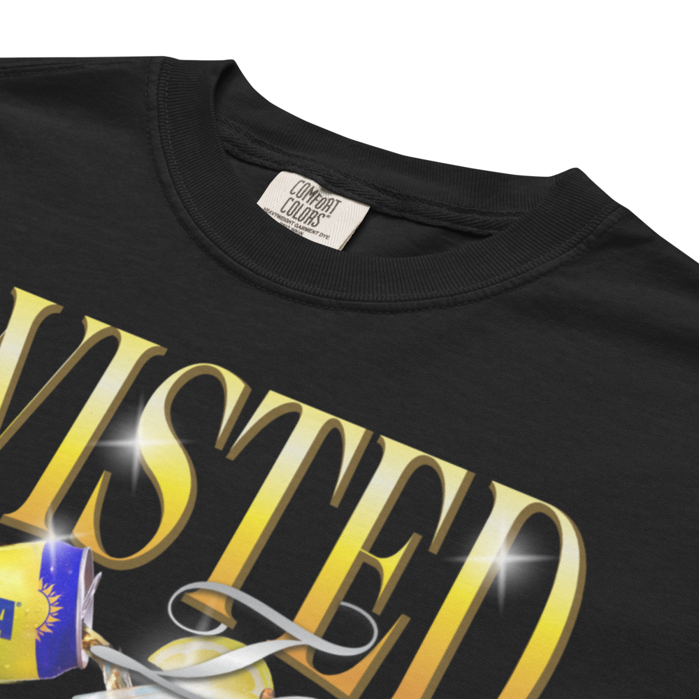 Close up shot showing comfort colors tag. Black Twisted Tea T‑shirt featuring large gold “Twisted Tea” lettering and a graphic of Twisted Tea Original cans and bottle splashing with iced tea.