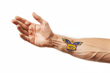 A forearm against a white background, featuring a colorful temporary tattoo of a yellow and blue eagle with outstretched wings on the outer wrist.