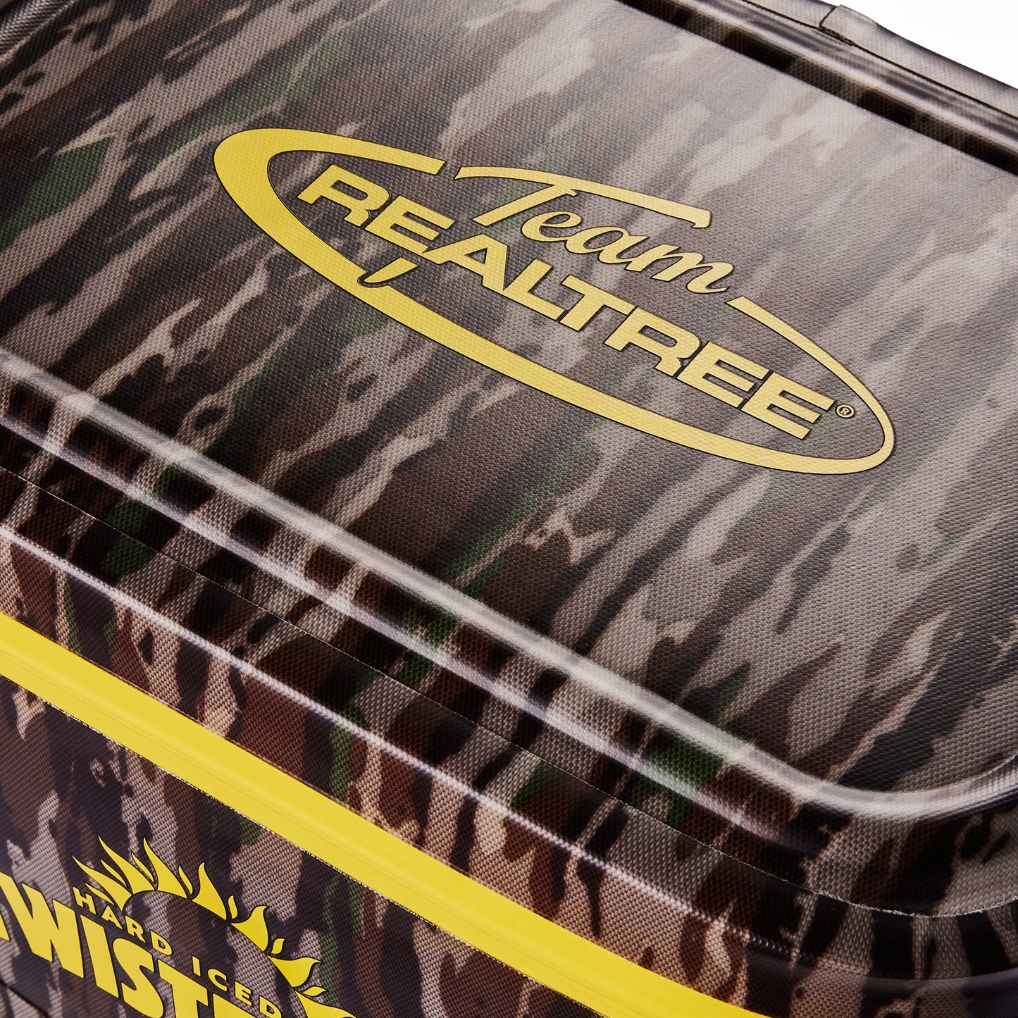 Close-up of a cooler lid featuring a dark camouflage pattern with a yellow Team Realtree logo and a bright yellow zipper line.