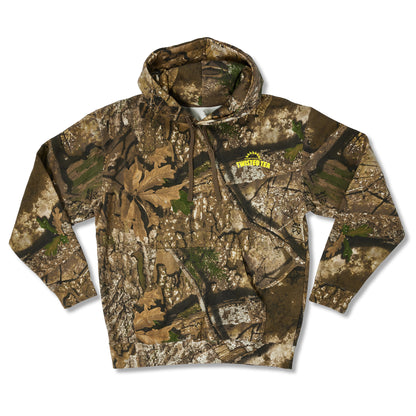 A long-sleeve pullover hoodie featuring an all-over woodland camouflage pattern with brown, beige, green, and black tones. A yellow  logo is printed on the left chest.